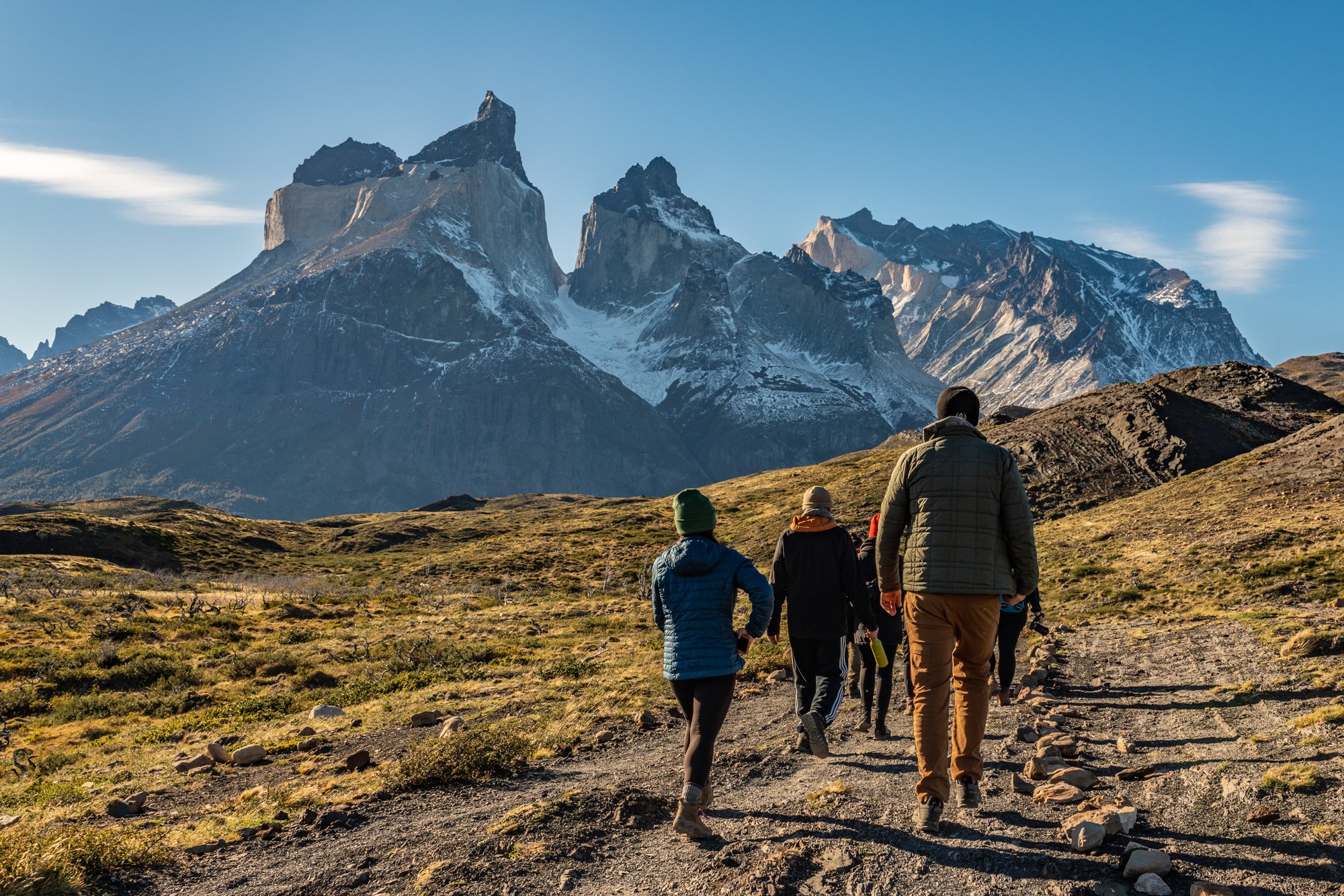 Essential trekking accessories for Torres del Paine: thermal beanie covering ears, versatile buff used as scarf or face mask, waterproof thermal gloves for rain or snow, and sunglasses to protect against the strong Patagonian sun. Key gear to stay safe and comfortable on long hikes in Patagonia’s trails.