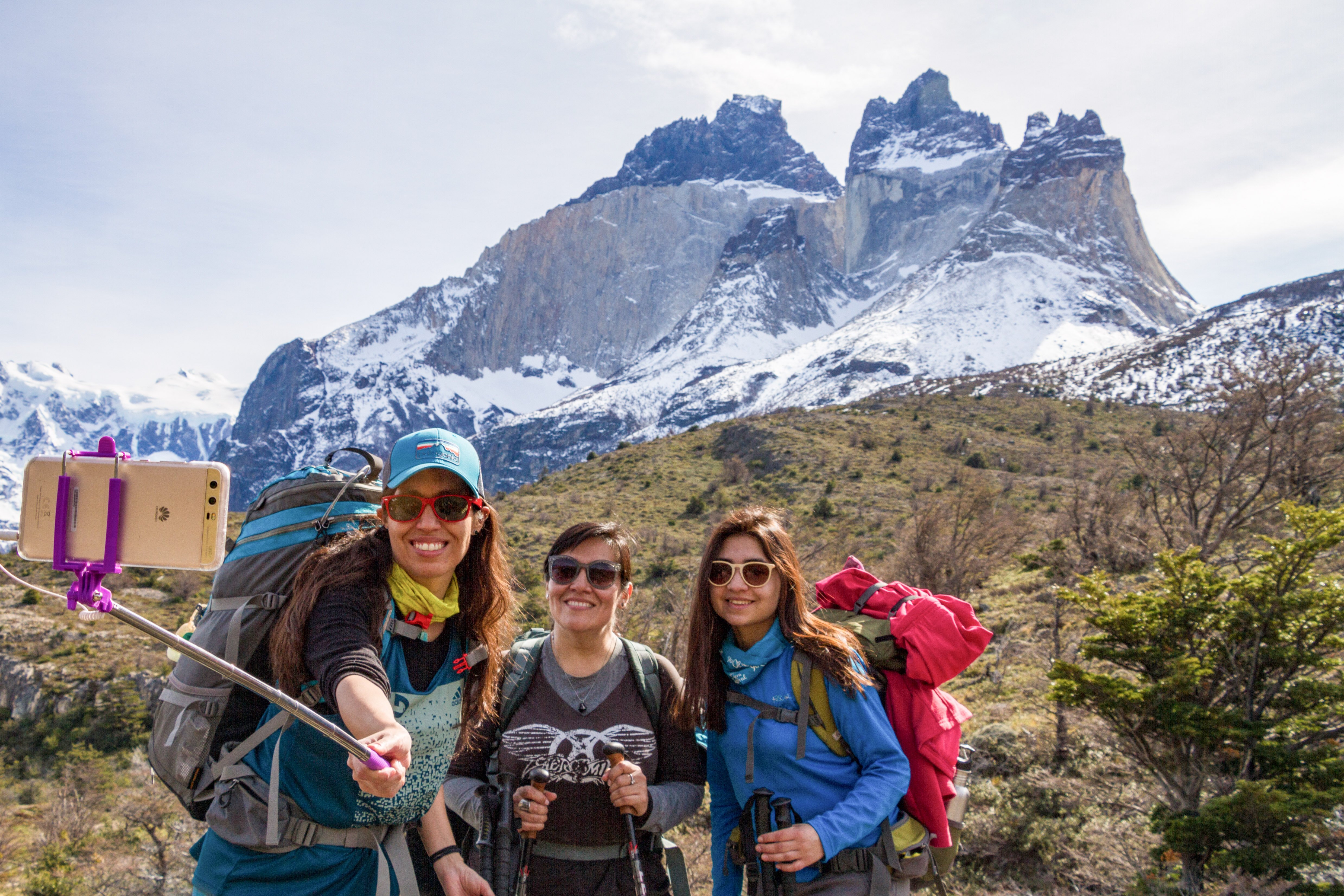 Grupo haciendo trekking en Torres del Paine con los picos de Los Cuernos detrás, creando recuerdos familiares duraderos en la Patagonia.